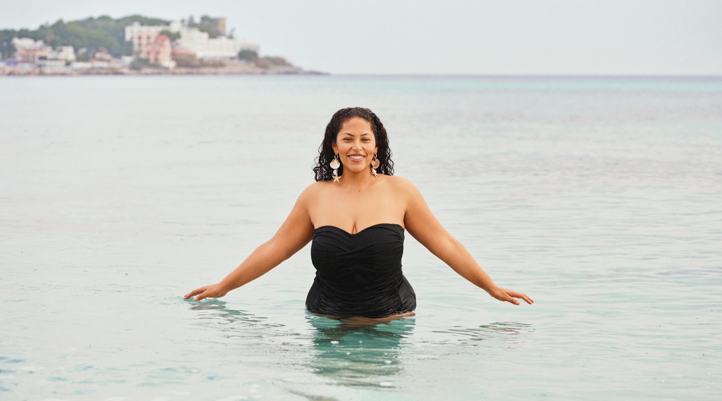 Modelka w białej górze od bikini w porcie, w otoczeniu kąpiących się osób.